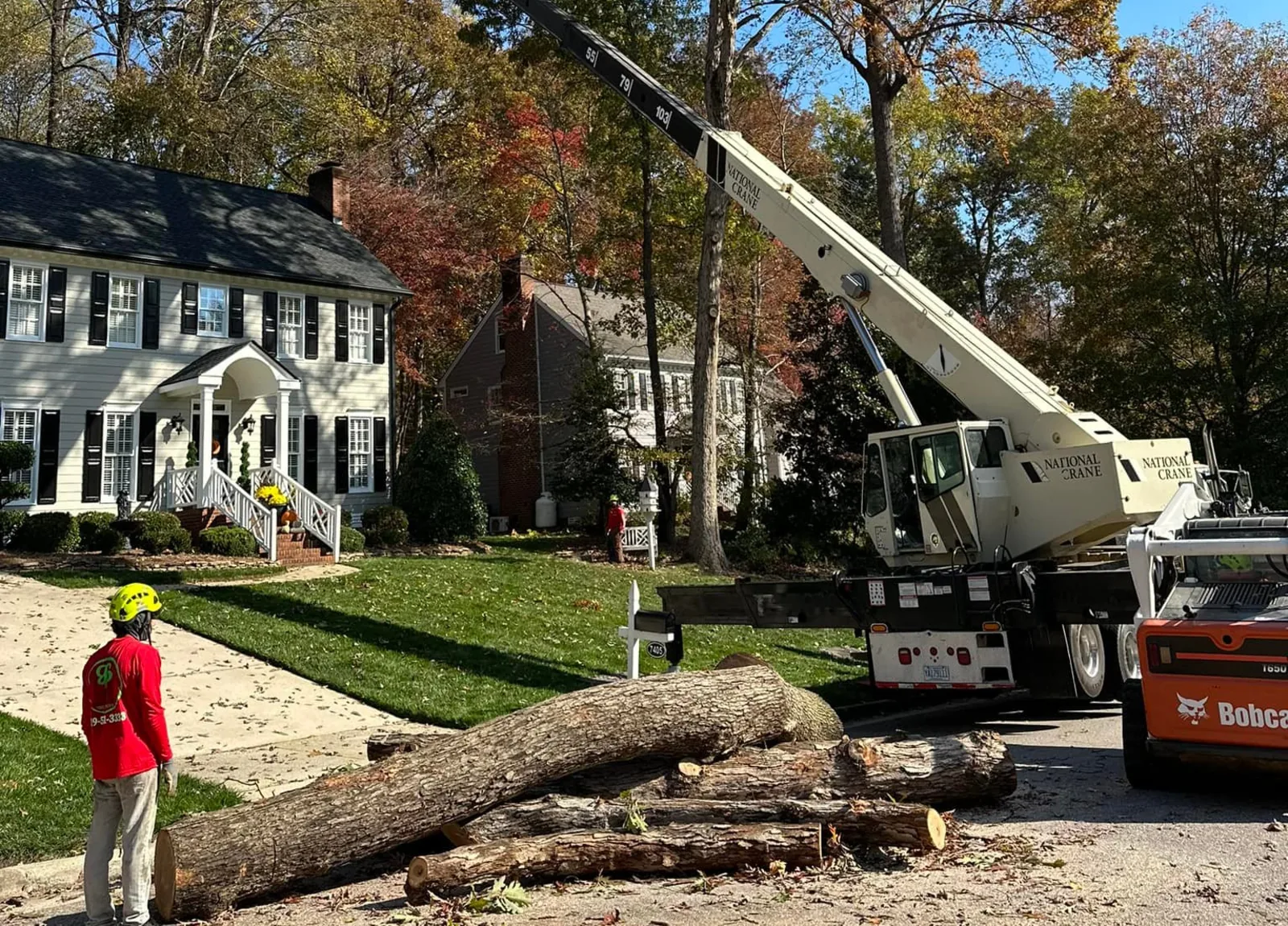 Guzman Brothers crane-assisted tree removal beside a two-story Triangle home