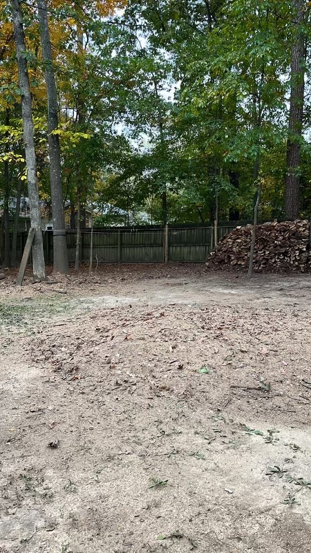 Cleared residential work area with a consolidated woodpile